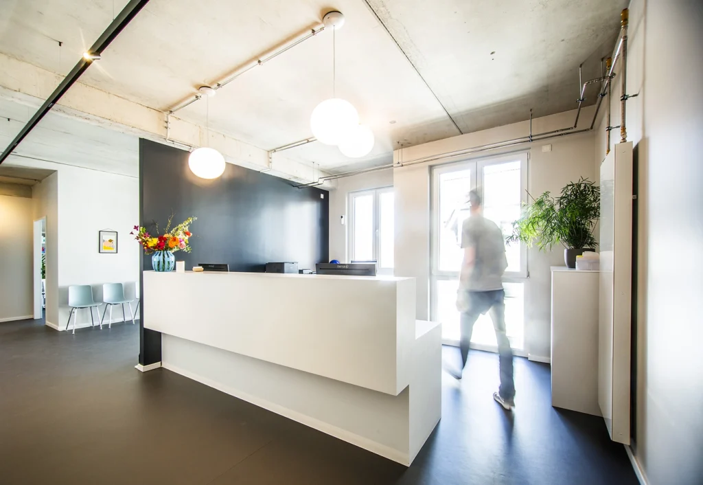 Seitenansicht Empfangstresen in einer Arztpraxis in Mineralwerkstoff weiß mit zwei Arbeitsplätzen und Stauraum.