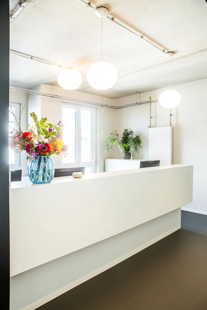 Empfangstresen in einer Arztpraxis in Mineralwerkstoff weiß mit zwei Arbeitsplätzen und Stauraum.