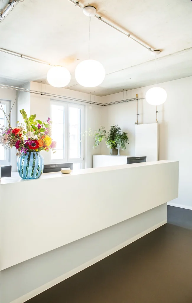 Empfangstresen in einer Arztpraxis in Mineralwerkstoff weiß mit zwei Arbeitsplätzen und Stauraum.